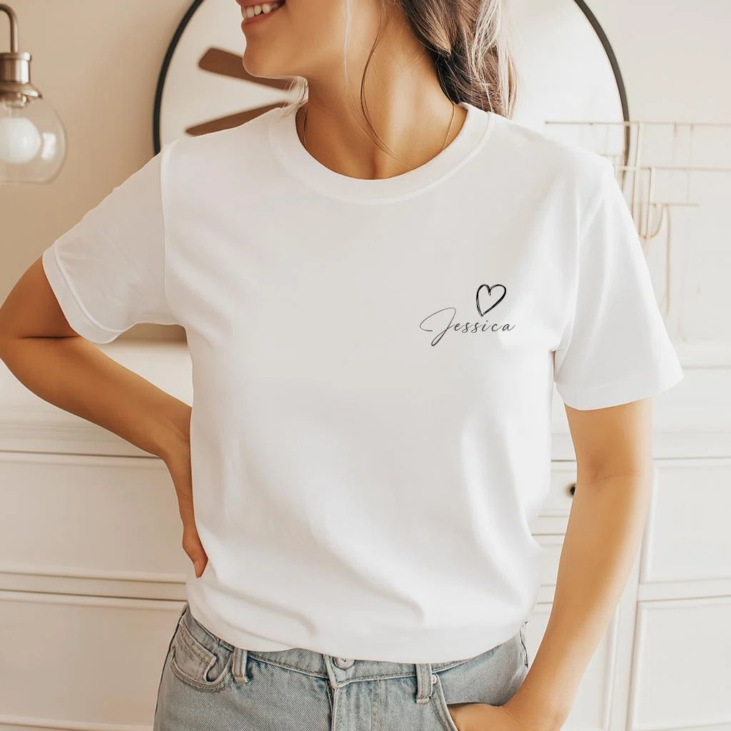 Weißes Kurzarm-T-Shirt in frontaler Ansicht, auf der linken Brust mit einem kleinen schwarzen Namensschriftzug in Schreibschrift und einer skizzierten Herzlinie bedruckt.