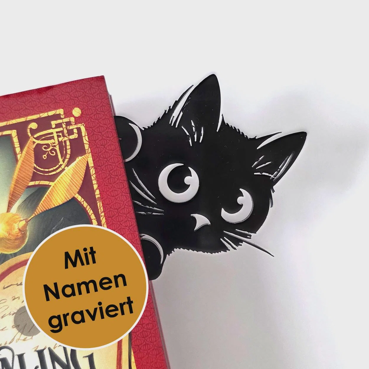 Katzen-Lesezeichen mit Namen kaufen: schwarze Katze mit großen weißen Augen und spitzen Ohren, die hinter einem roten Buch hervorschaut. Ein Hinweis nennt die Namensgravur.