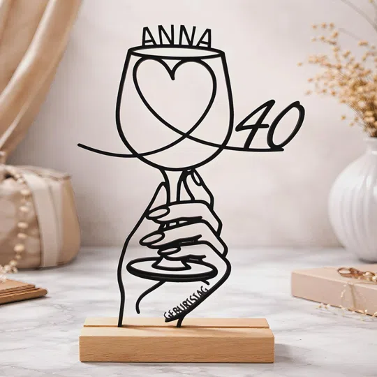 Aufsteller zum 40. Geburtstag personalisiert kaufen: Schwarze Linien formen Hände mit Weinglas und Herz; darüber steht ein Name, seitlich die 40, darunter ein heller Sockel.