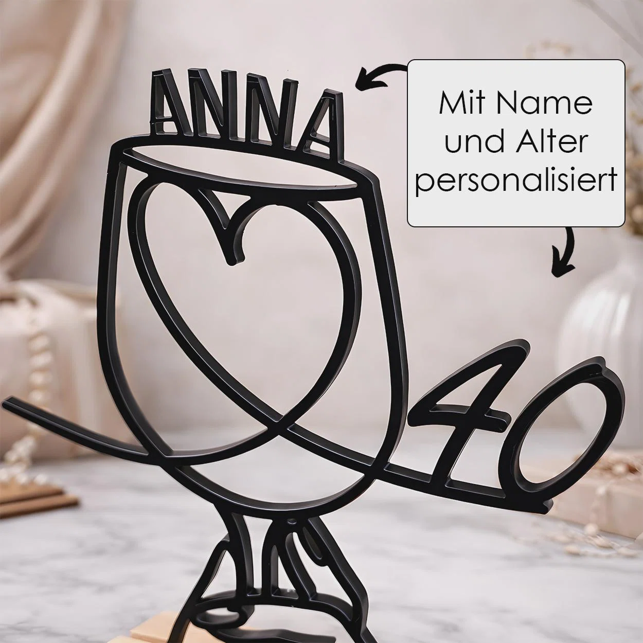 Schwarze, freistehende Vogelsilhouette mit herzförmigem Körper, personalisiertem Namen über dem Kopf und Alter im geschwungenen Schwanz. Pfeile weisen auf beide Wunschangaben hin.