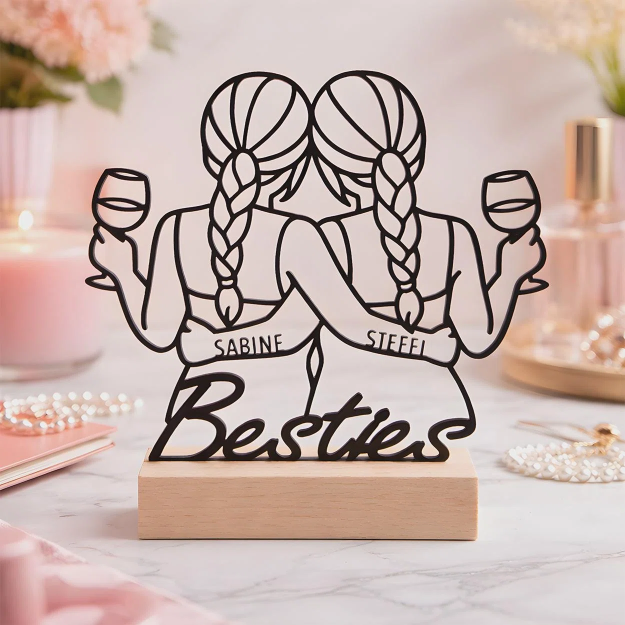 Personalisierten Besties-Aufsteller kaufen: schwarze Linienfigur zweier Freundinnen mit Zöpfen und Weingläsern, Namen und „Besties“-Schriftzug auf einem hellen Sockel.