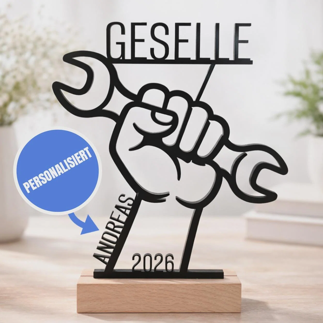 Gesellen-Aufsteller mit Namen kaufen: schwarze Faust mit Schraubenschlüssel, darüber „Geselle“, ergänzt um Name und Jahreszahl auf einem hellen Sockel.