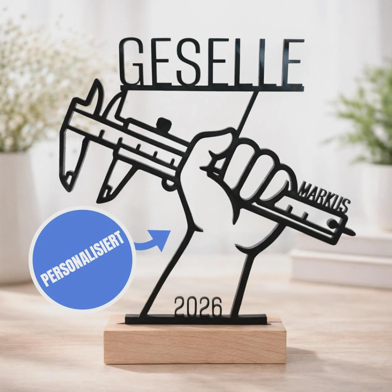 Gesellen-Aufsteller personalisiert kaufen: schwarze Silhouette einer Hand mit Messschieber, Schriftzug „Geselle“, Name und Jahreszahl 2026 auf einem hellen Sockel.