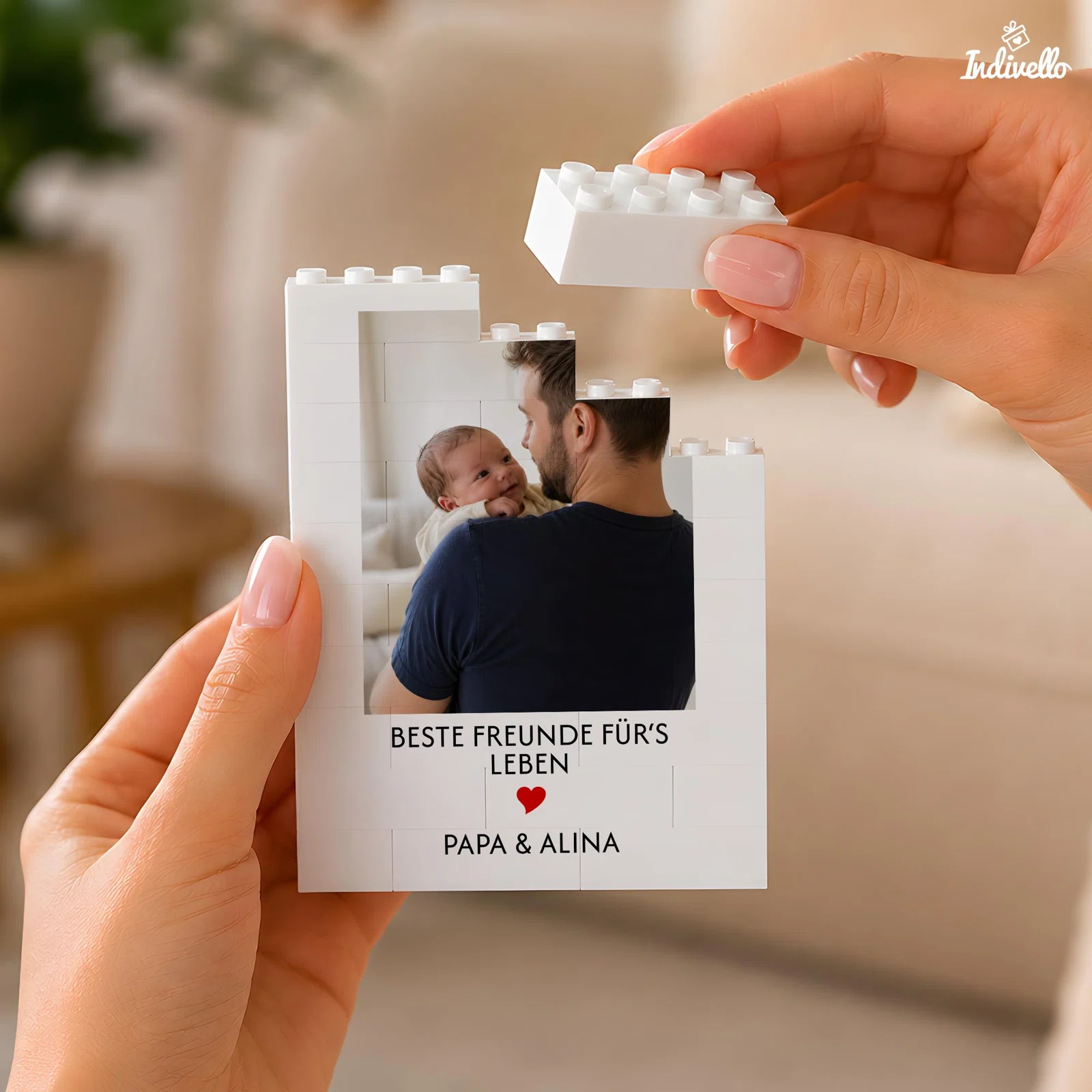 Weißes Fotopuzzle in Bausteinform mit dem Motiv einer erwachsenen Person, die ein Baby hält, sowie dem Spruch „Beste Freunde fürs Leben“ und rotem Herz. Ein oberer Stein wird abgehoben.