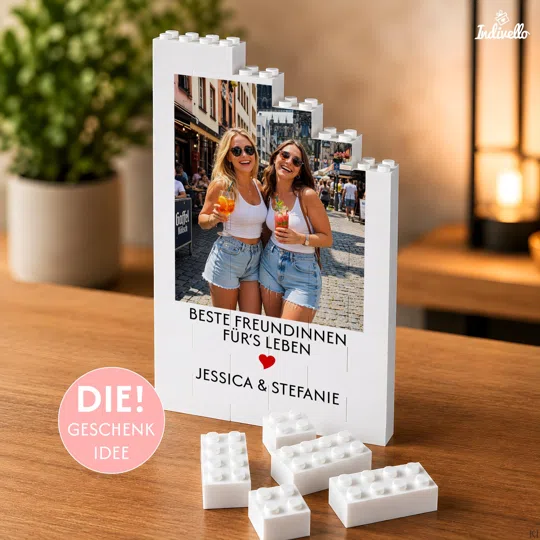 Fotogeschenk aus Klemmbausteinen personalisiert bestellen: weißer, stufenförmiger Fotoaufsteller mit Hochformatfoto, Spruch, Namen und rotem Herz; lose Bausteine liegen davor.