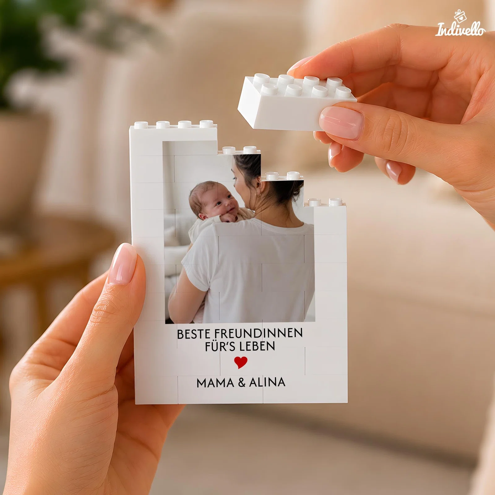 Personalisierbares Fotomotiv aus weißen Klemmbausteinen, in Händen gehalten. Zu sehen sind ein Foto mit erwachsener Person und Baby, der Spruch „Beste Freundinnen fürs Leben“ und ein rotes Herz.