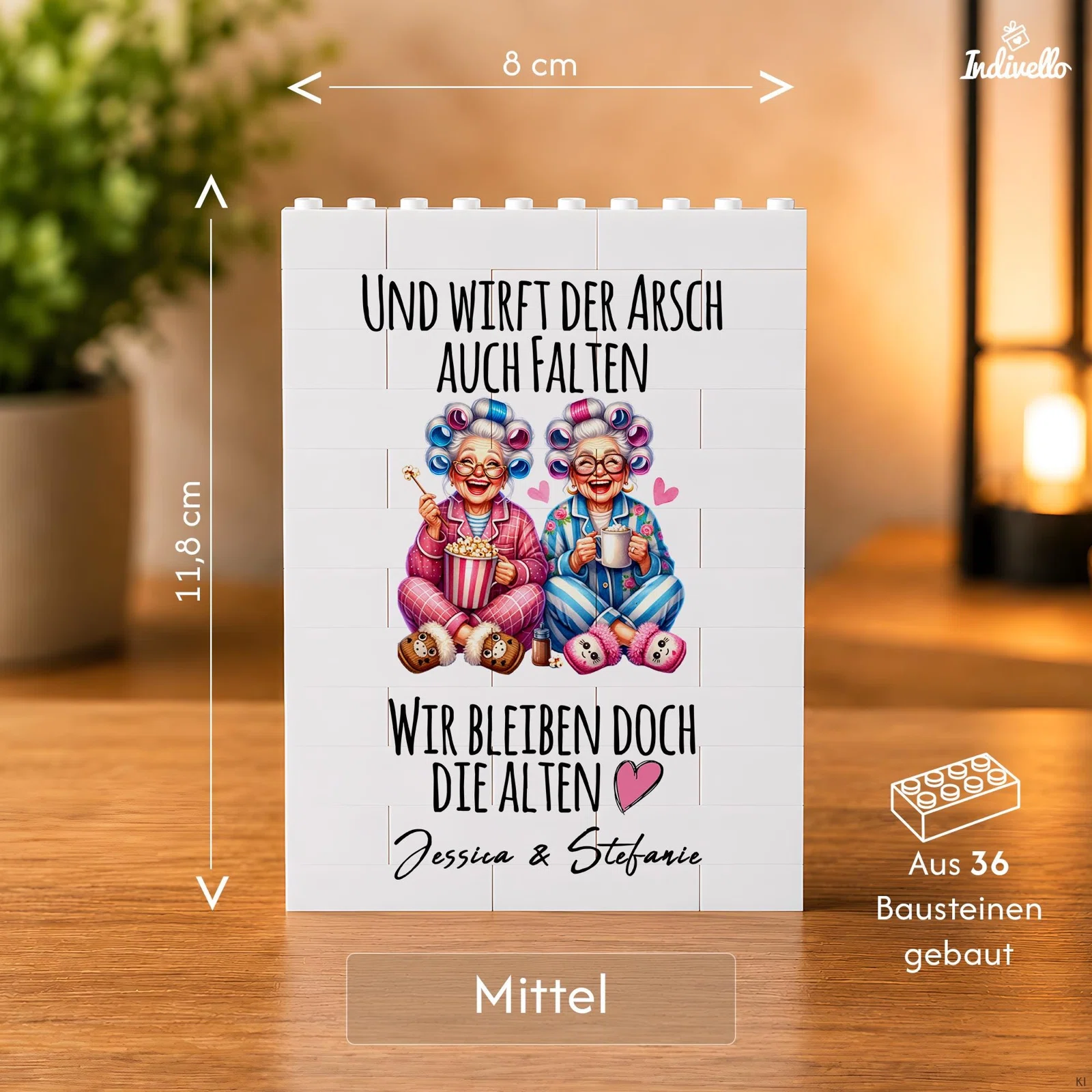 Größenansicht „Mittel“: 8 cm breite und 11,8 cm hohe Tafel aus 36 weißen Bausteinen. Bedruckt mit zwei Frauen im Schlafanzug, Herzchen und dem Spruch „Und wirft der Arsch auch Falten, wir bleiben doch die Alten“.