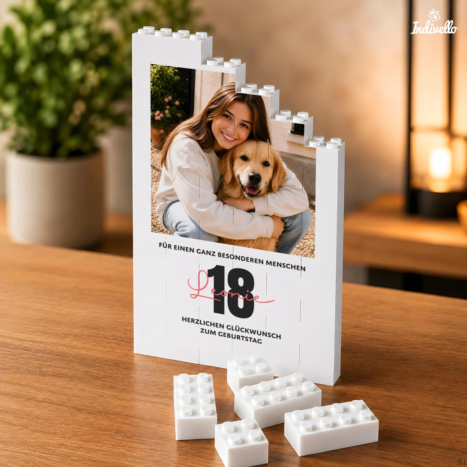 Aufrecht stehende weiße Fototafel aus Klemmbausteinen mit stufenförmigem Rand, Foto einer Person mit Hund und Glückwunsch zum 18. Geburtstag. Lose weiße Bausteine liegen davor auf dem Tisch.