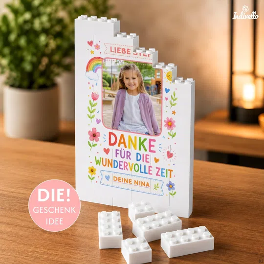 Personalisiertes Dankesgeschenk bestellen: weißer Klemmbaustein-Fotoaufsteller mit Kinderfoto, bunten Blumen und „Danke für die wundervolle Zeit“, neben losen Bausteinen auf einem Holztisch.