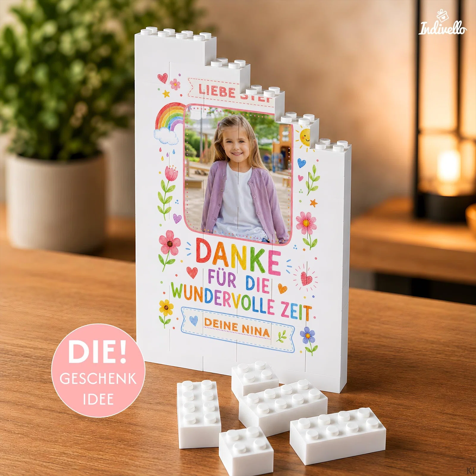 Personalisiertes Dankesgeschenk bestellen: weißer Klemmbaustein-Fotoaufsteller mit Kinderfoto, bunten Blumen und „Danke für die wundervolle Zeit“, neben losen Bausteinen auf einem Holztisch.