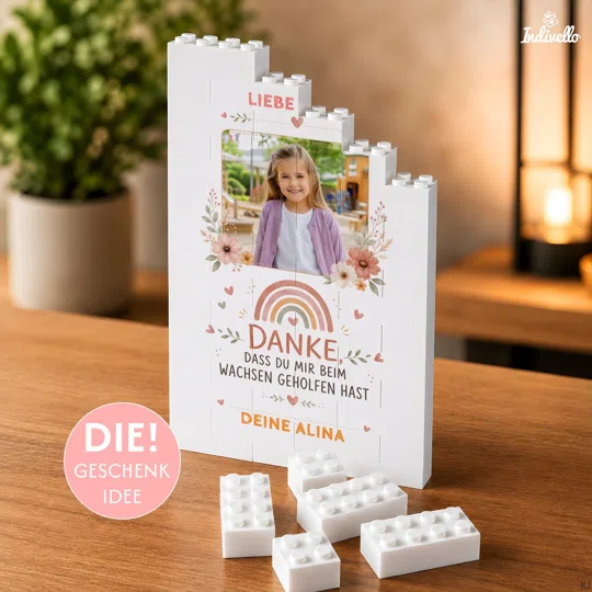 Foto-Dankesgeschenk aus Klemmbausteinen bestellen: weißer Aufsteller mit Porträt, Blumen, Regenbogen und dem Spruch „Danke, dass du mir beim Wachsen geholfen hast“.