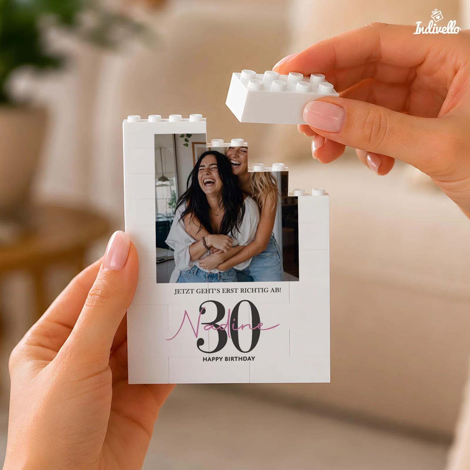 Weiße, zusammensetzbare Fototafel in Bausteinoptik, frontal in zwei Händen gehalten. Sie trägt ein Foto zweier lachender Personen sowie „30“, „Happy Birthday“ und einen Namen in Rosa.