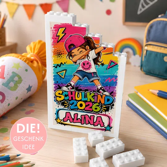 Schulkind-Geschenk mit Namen bestellen: weiße Klemmbaustein-Tafel mit stufiger Oberkante, buntem Graffiti-Motiv und einem gezeichneten Schulkind in Dab-Pose über „Schulkind 2025“.
