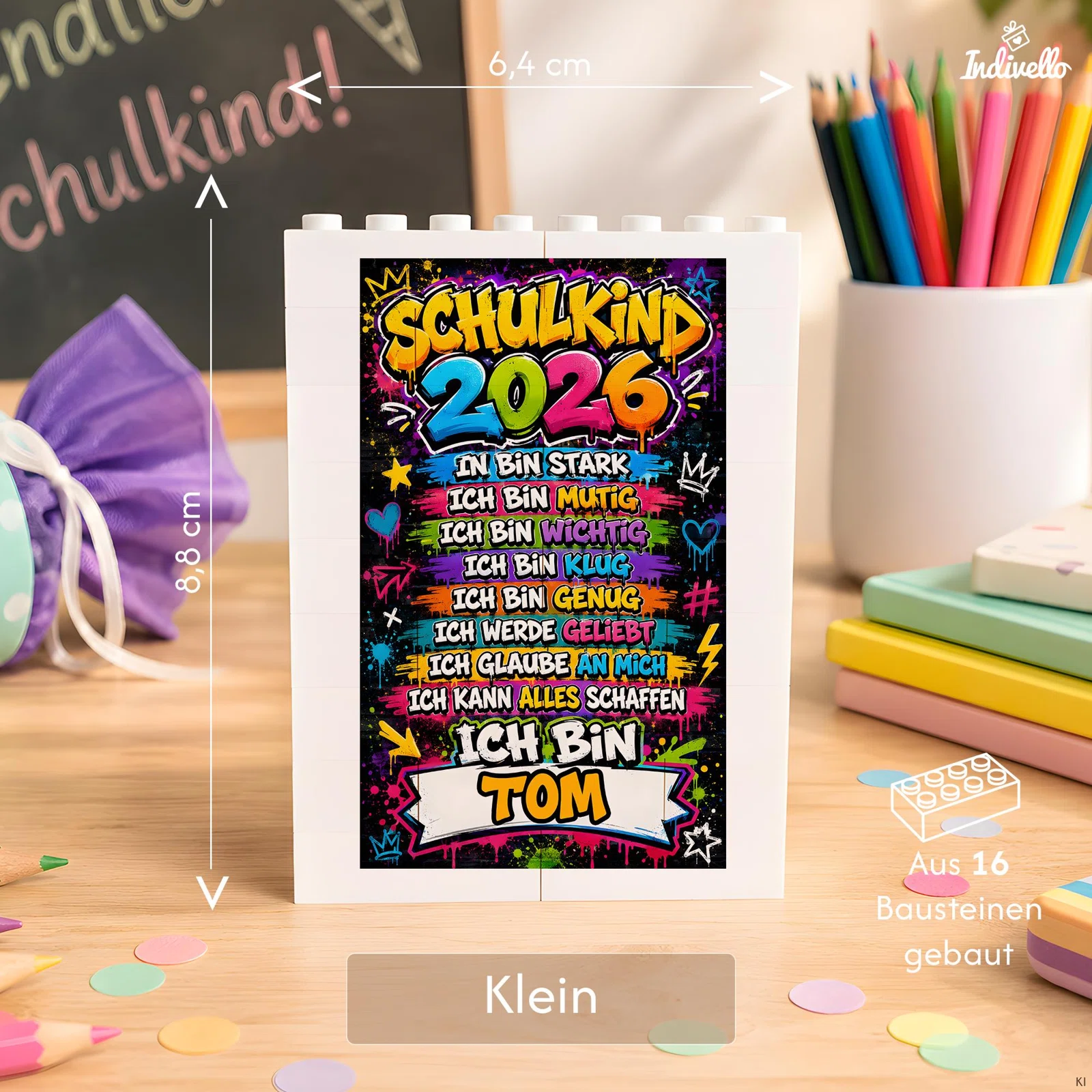 Größenansicht eines kleinen, frontal gezeigten Bausteinrahmens: 6,4 cm breit, 8,8 cm hoch und aus 16 Steinen gebaut. Der bunte Einsatz trägt „Schulkind 2026“ und stärkende Ich-Sätze.