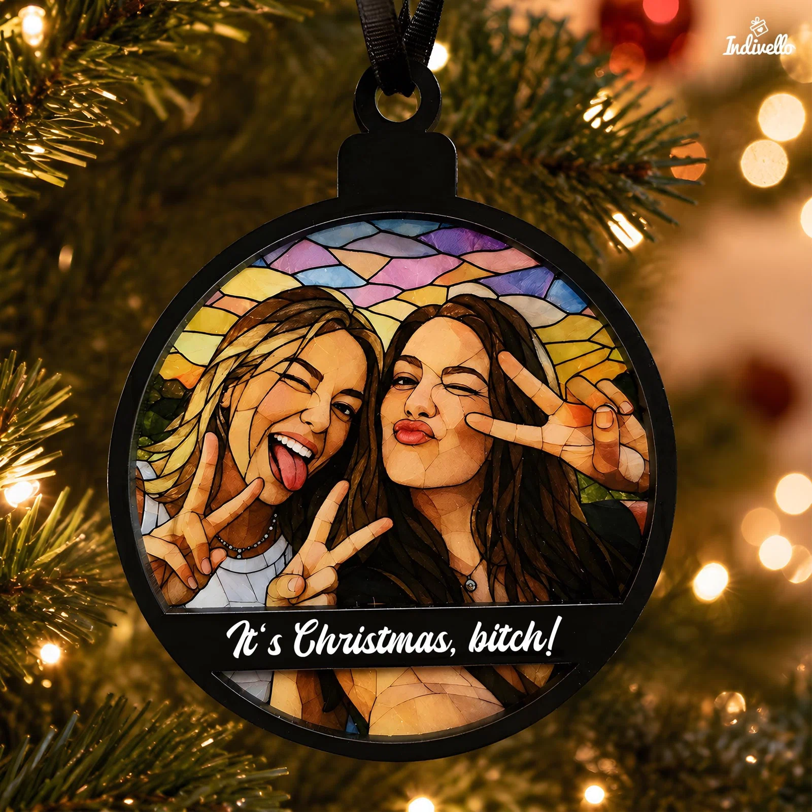 Runder schwarzer Weihnachtsanhänger am Tannenbaum, gestaltet wie ein buntes Glasmosaik mit zwei posierenden Personen und Victory-Zeichen. Auf der Querleiste steht „It’s Christmas, bitch!“.