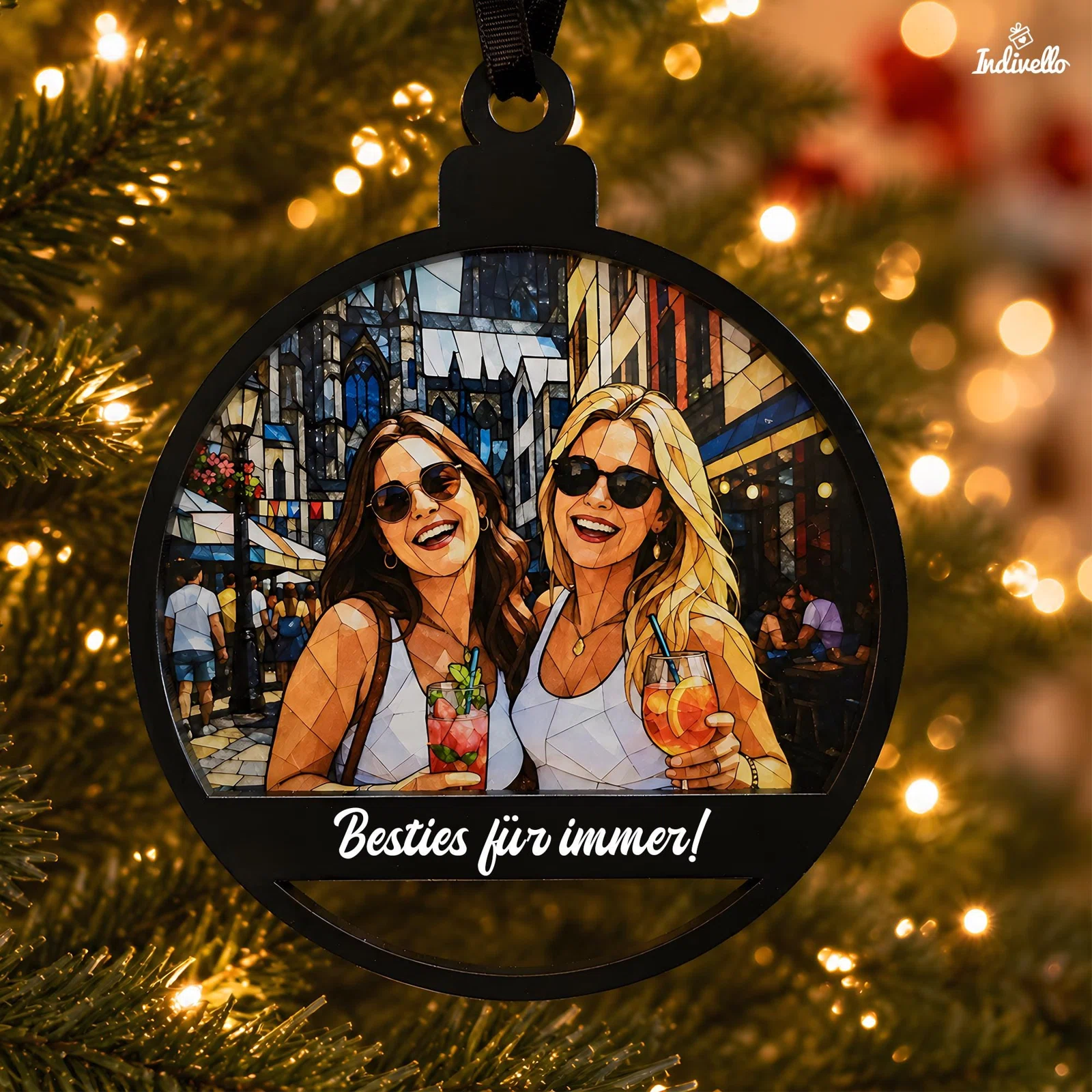 Runder schwarzer Weihnachtsanhänger vor einem beleuchteten Tannenbaum, mit zwei Frauen samt Sonnenbrillen und Getränken im bunten Mosaikstil. Darunter steht „Besties für immer!“