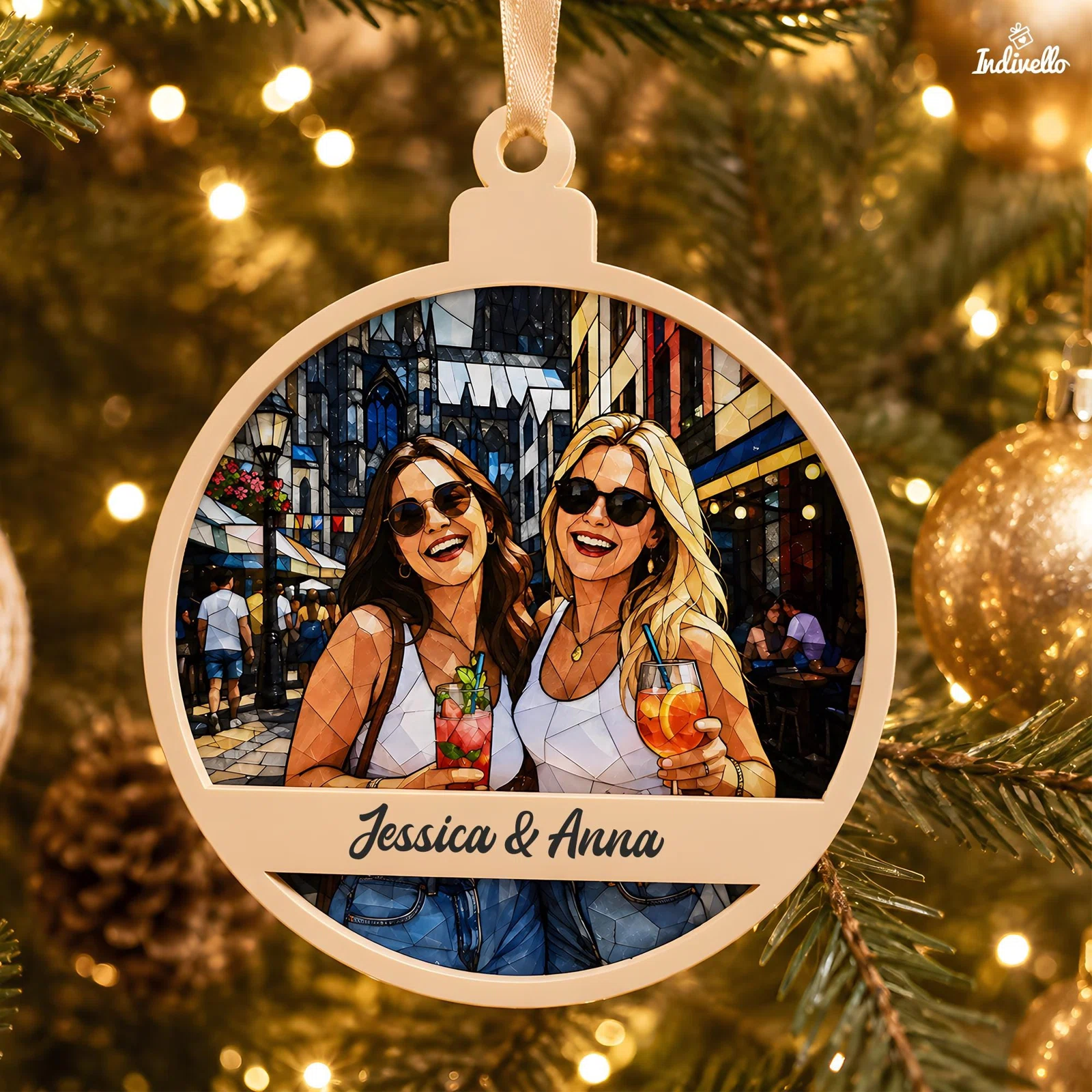 Runder, cremefarbener Weihnachtsanhänger am Tannenbaum, frontal fotografiert. Die mosaikartige Illustration zeigt zwei Frauen mit Sonnenbrillen und Getränken in einer Stadtgasse, darunter ein Namenszug.
