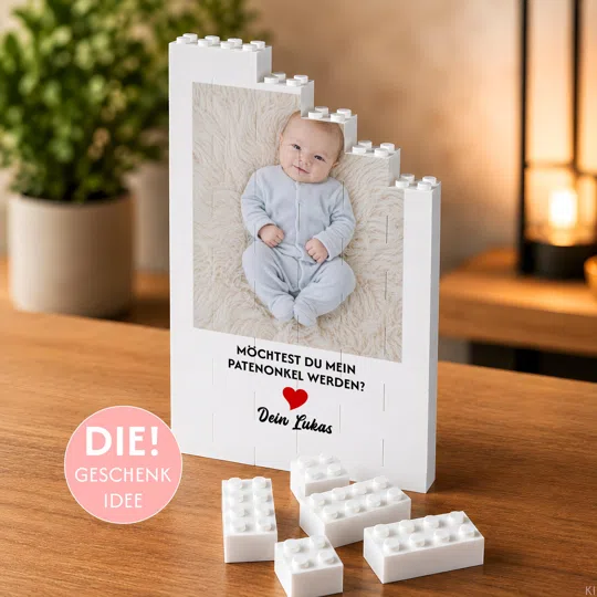 Patenonkel-Fotogeschenk bestellen: weißer Klemmbaustein-Aufsteller mit Babyfoto und der Frage „Möchtest du mein Patenonkel werden?“, neben einzelnen Bausteinen auf einem Holztisch.