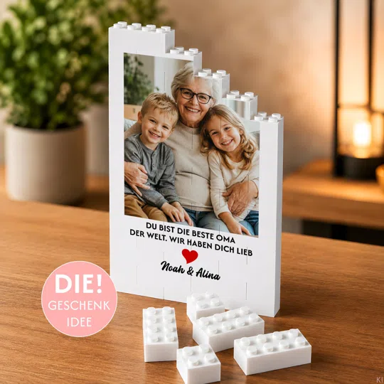 Fotogeschenk für Oma bestellen: weißer Klemmbaustein-Aufsteller mit Familienfoto, rotem Herz und „Du bist die beste Oma der Welt. Wir haben dich lieb“.