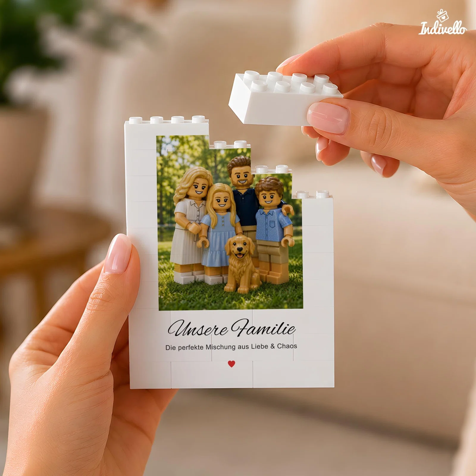 Weißer Bilderrahmen in Bausteinoptik, von zwei Händen gehalten und mit einem Noppenstein ergänzt. Das Motiv zeigt vier Spielfiguren mit Hund im Grünen sowie den Spruch „Unsere Familie“.