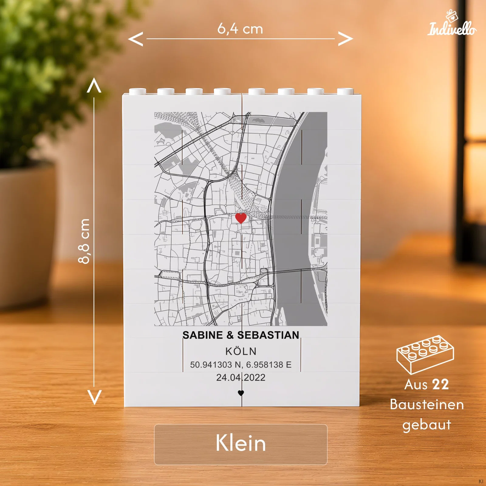 Kleine weiße Baustein-Tafel aus 22 Steinen mit grauem Stadtplan von Köln, rotem Herzmarker sowie personalisierbaren Namen, Koordinaten und Datum. Angegebene Größe: 6,4 × 8,8 cm.