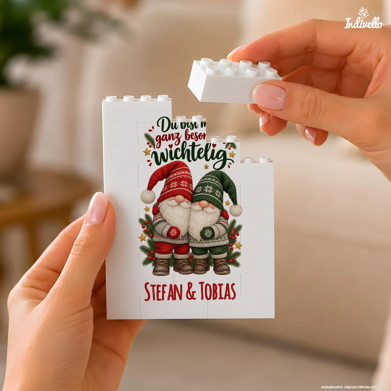 Nahaufnahme zweier Hände, die einen weißen Klemmbaustein auf ein rechteckiges Bausteinbild setzen. Darauf sind zwei Weihnachtswichtel in Rot und Grün mit der Aufschrift „Du bist mir ganz besonders wichtelig“ sowie den Namen „Stefan & Tobias“ abgebildet.