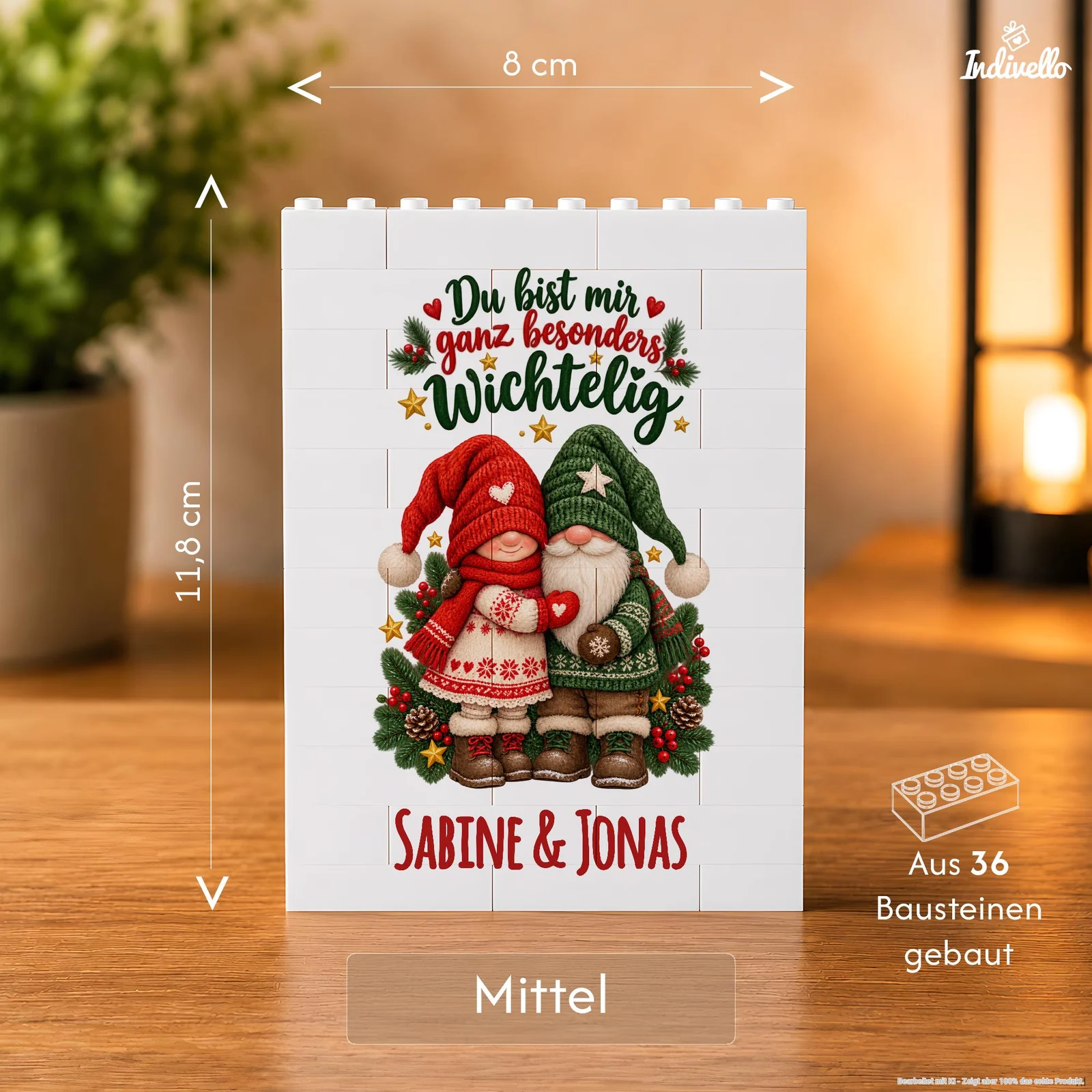 Frontalansicht einer weißen, aus 36 Bausteinen zusammengesetzten Dekotafel auf einem Holztisch. Sie zeigt zwei Weihnachtswichtel in Rot, Grün und Weiß, umgeben von Tannenzweigen, Beeren und Sternen, mit dem Spruch „Du bist mir ganz besonders wichtelig“ und den Namen „Sabine & Jonas“.