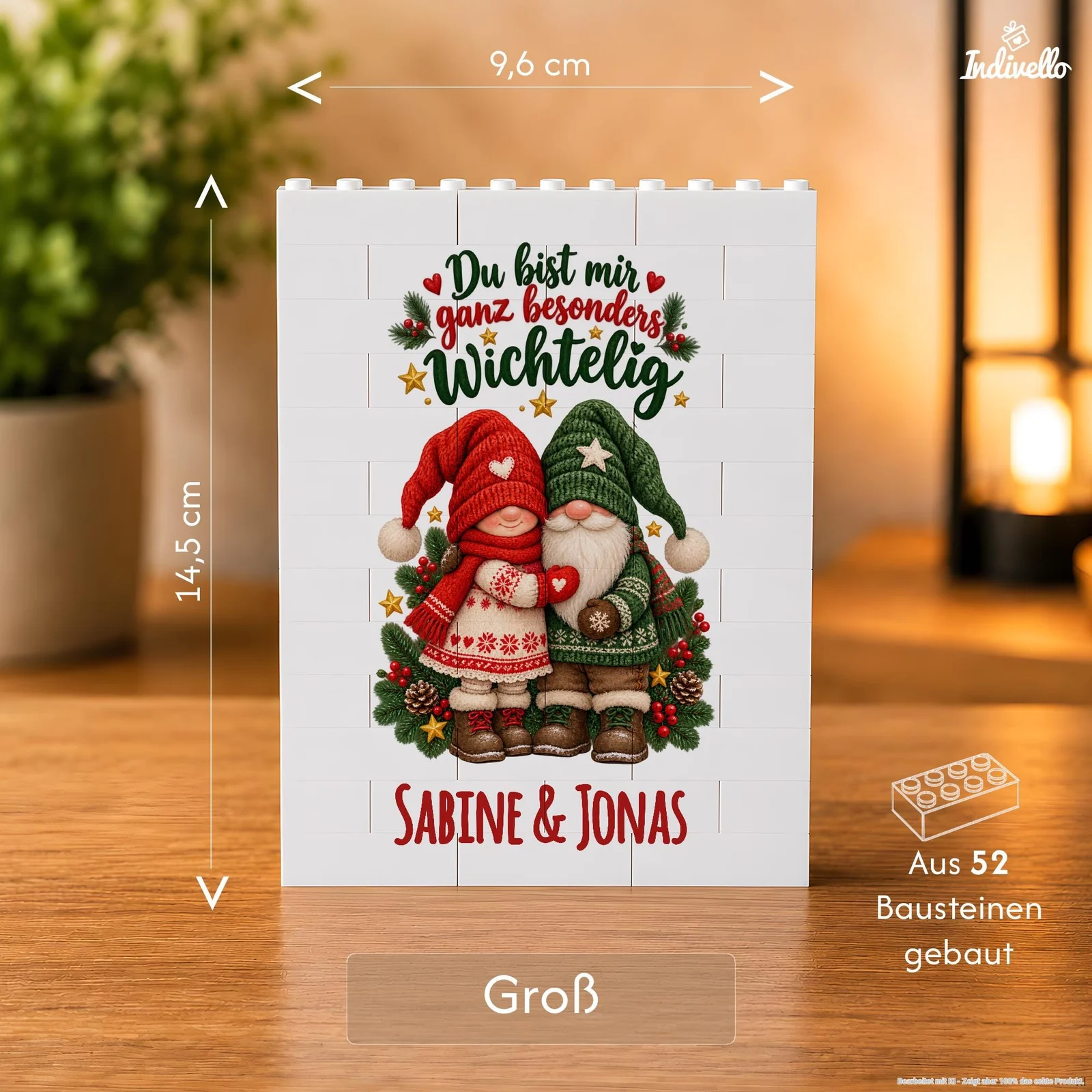 Frontalansicht einer weißen, rechteckigen Bausteinplatte auf einem Holztisch, bedruckt mit zwei Weihnachtswichteln in Rot und Grün, Tannenzweigen und dem Spruch „Du bist mir ganz besonders wichtelig“ sowie „Sabine & Jonas“. Die Infografik kennzeichnet 9,6 cm Breite, 14,5 cm Höhe und 52 Bausteine; im Hintergrund leuchten warme Lampen.