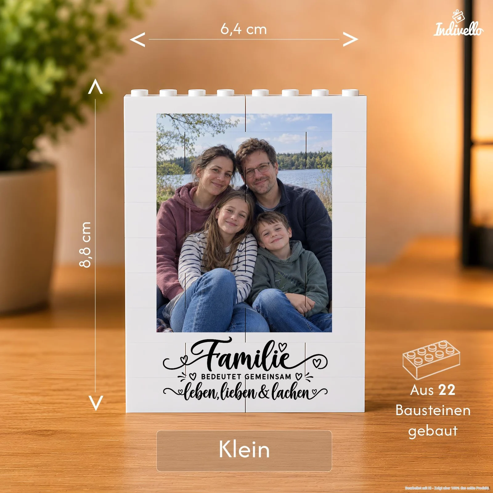 Frontalansicht eines kleinen weißen Bilderrahmens aus 22 Bausteinen auf einem Holztisch, bestückt mit einem Familienfoto am See. Unter dem Foto steht dekorativ „Familie bedeutet gemeinsam leben, lieben & lachen“; der Hintergrund ist warm beleuchtet und unscharf.